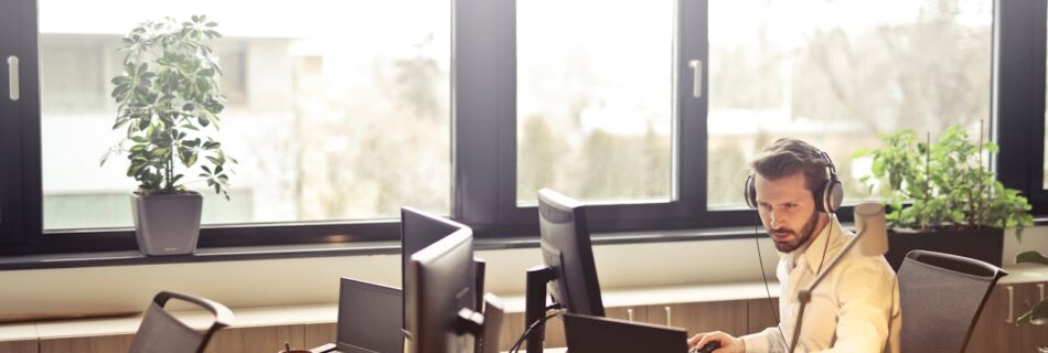 Man With Headphones Facing Computer Monitor